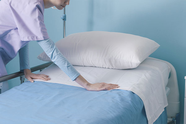 Kliniken & Reha - Bettwäsche und Frotteewäsche. Hier im Bild: Pflegekraft bezieht ein Bett frisch.